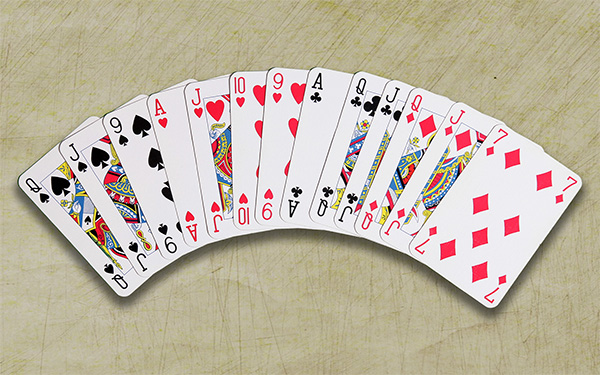 A photograph of thirteen playing cards laying on a wooden background