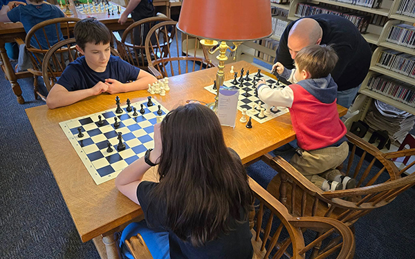 A table with two chess sets and a lamp
